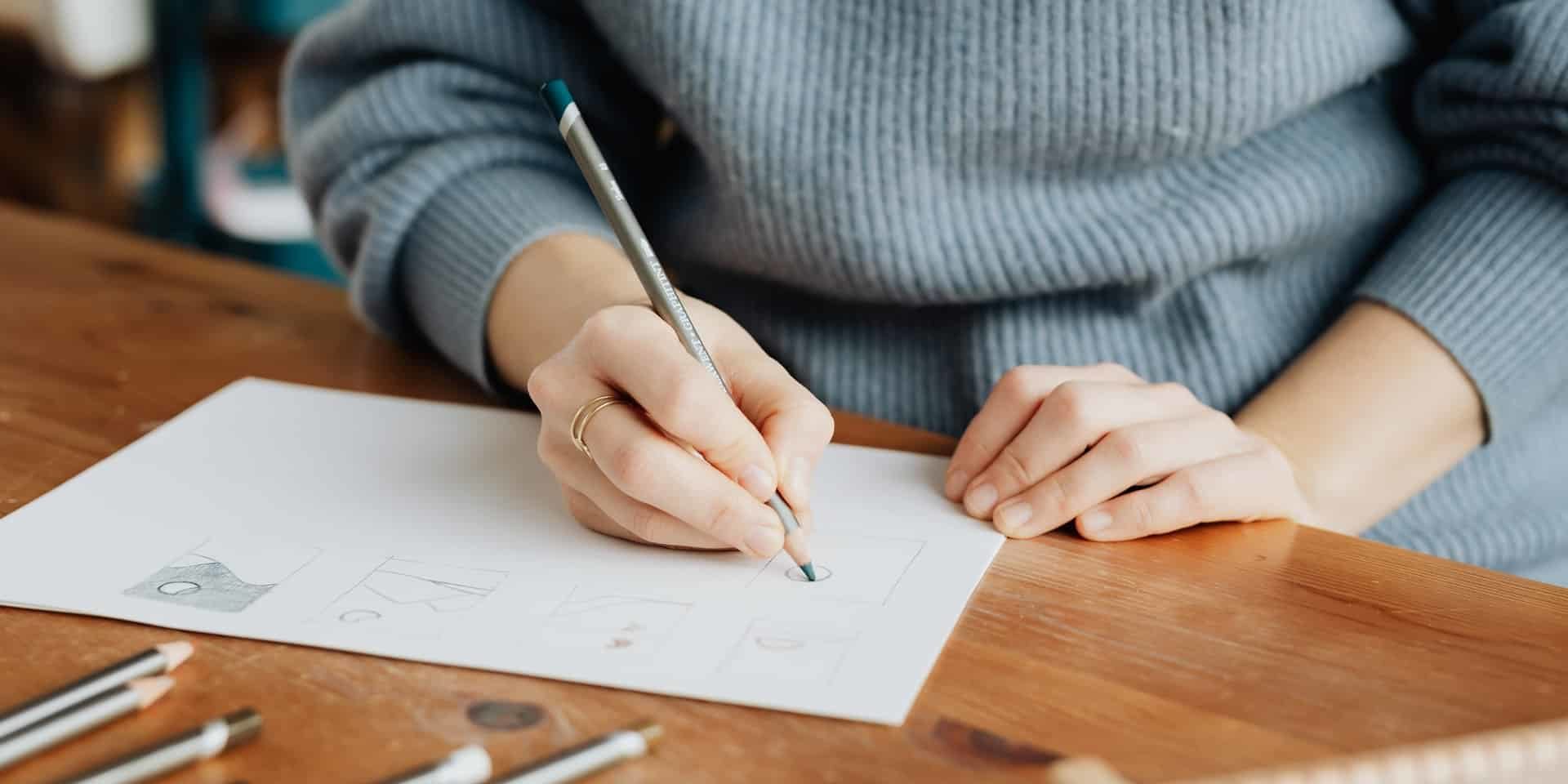 crop-faceless-female-artist-making-scheme-with-pencil-on-4219149
