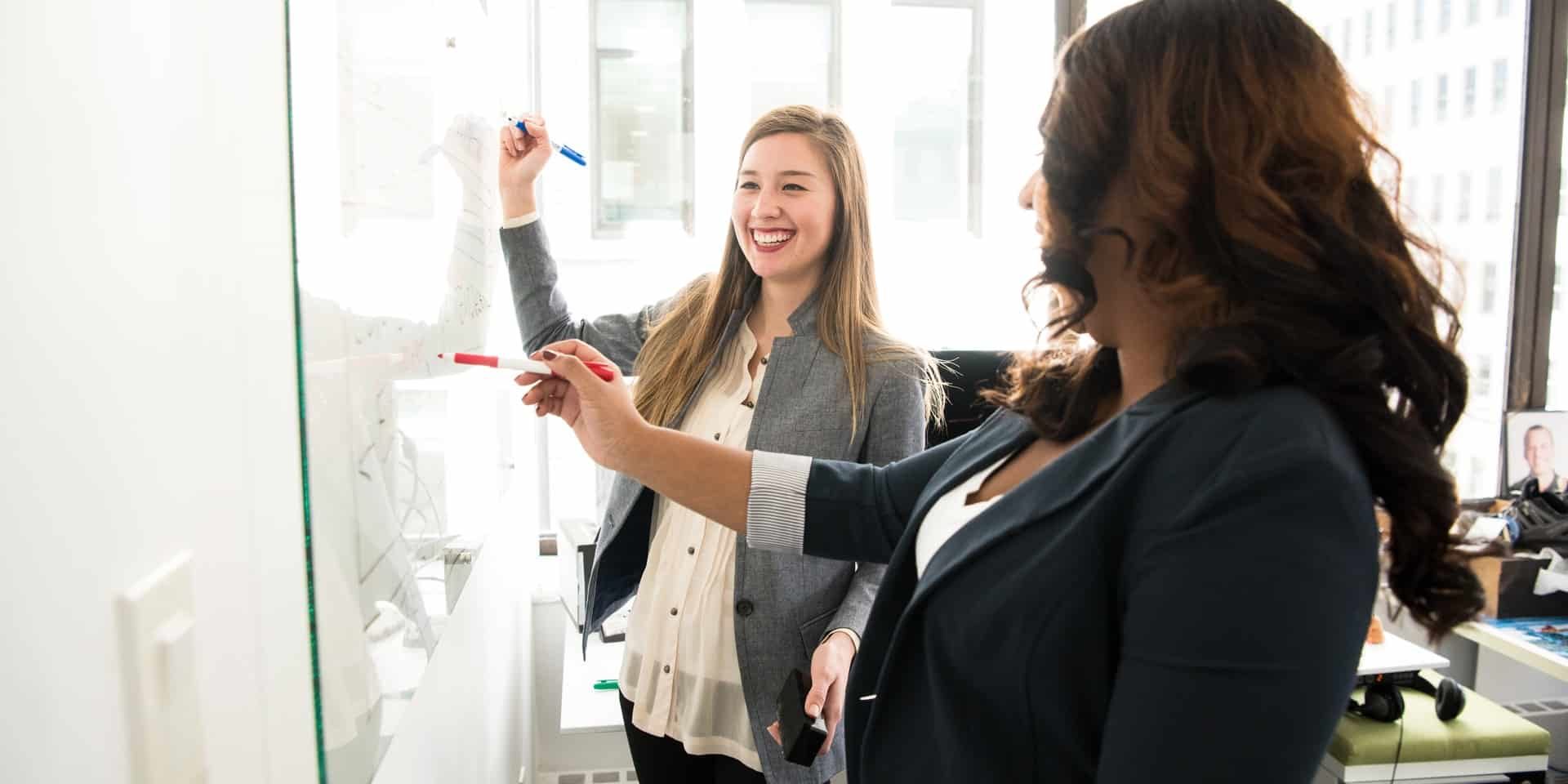 two-women-in-front-of-dry-erase-board-1181533